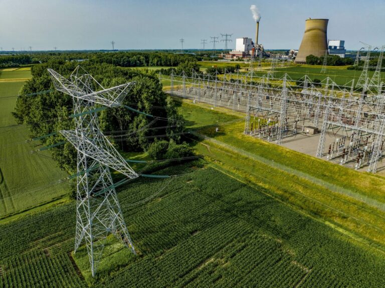 Aerial view of ADVANCE Act power lines leading to an industrial plant amidst green fields